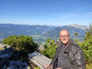 Jan Niemeijer zit op een bankje, met bergen op de achtergrond